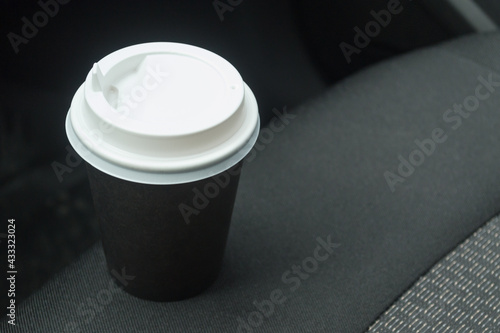Cardboard cup with coffee on the car seat. Stop on the road. Morning coffee.