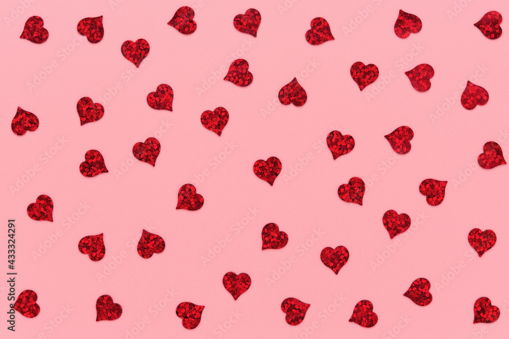 Red heart shaped confetti pattern on pink abstract background.