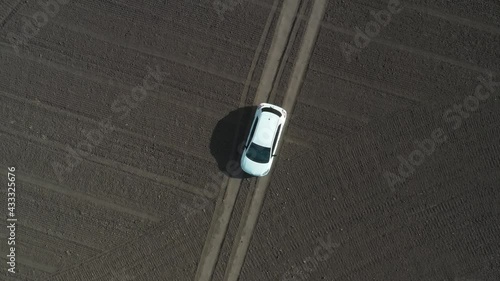 empty field top view, on a narrow road, a trail is symmetrically white car, graphic, geometric space, landscape abstraction