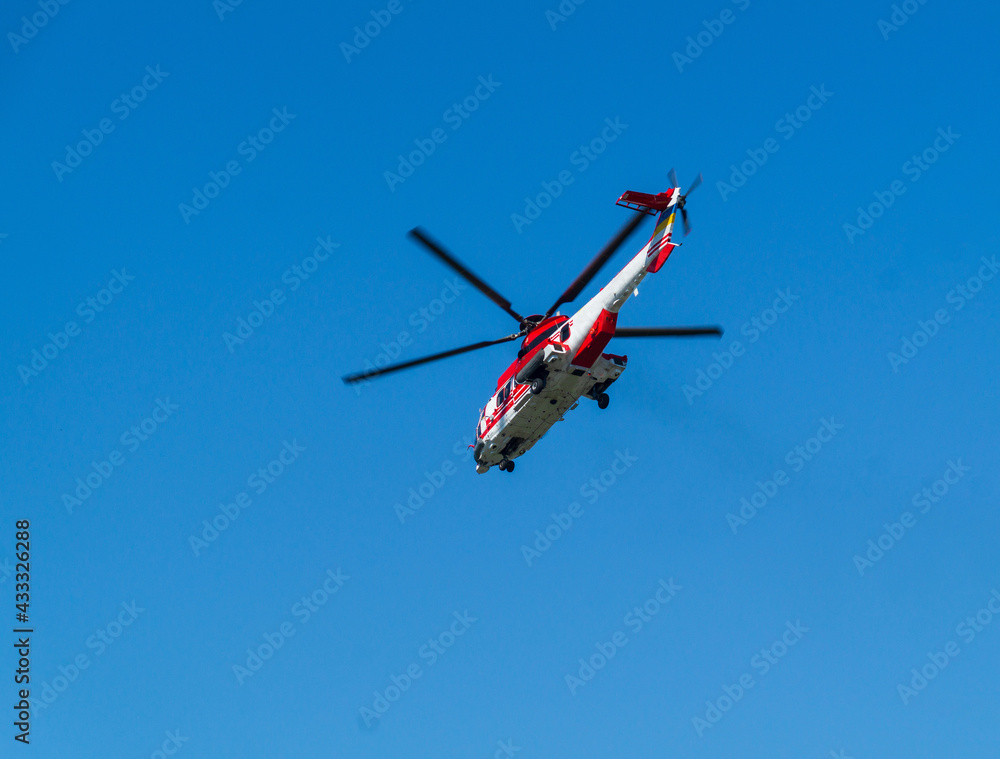 Red rescue helicopter moving in blue sky. Rapid medical assistance or rescue by helicopter Red rescue helicopter moving in blue sky. Rapid medical assistance or rescue by helicopter