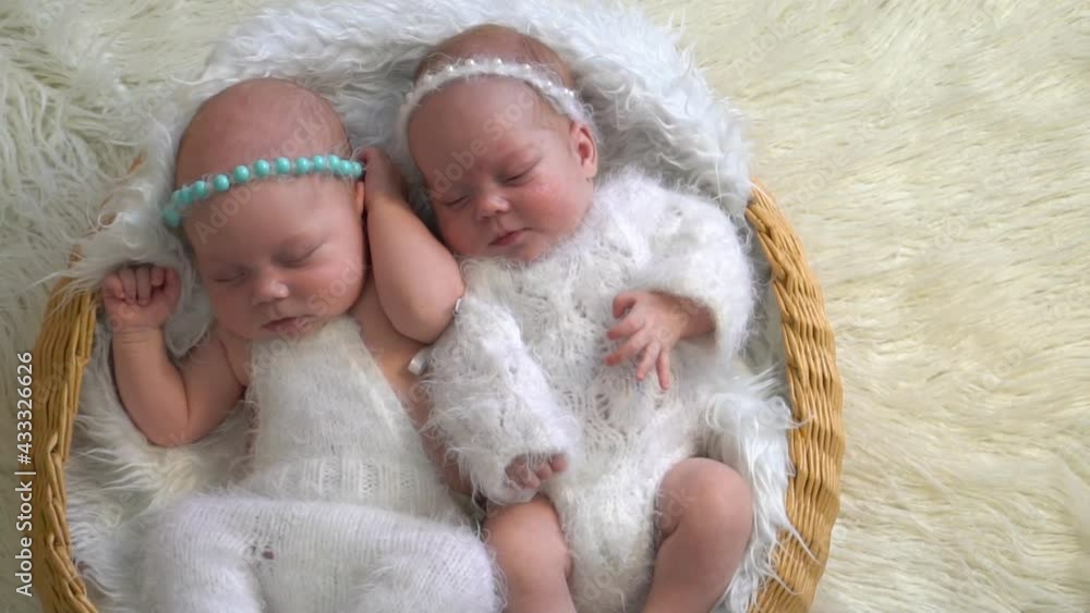 Newborn twins girls sleeping inside the wicker basket Newborn twins girls sleeping inside the wicker basket