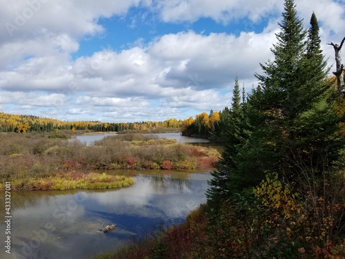 Fall colored trees around a lake with clouds