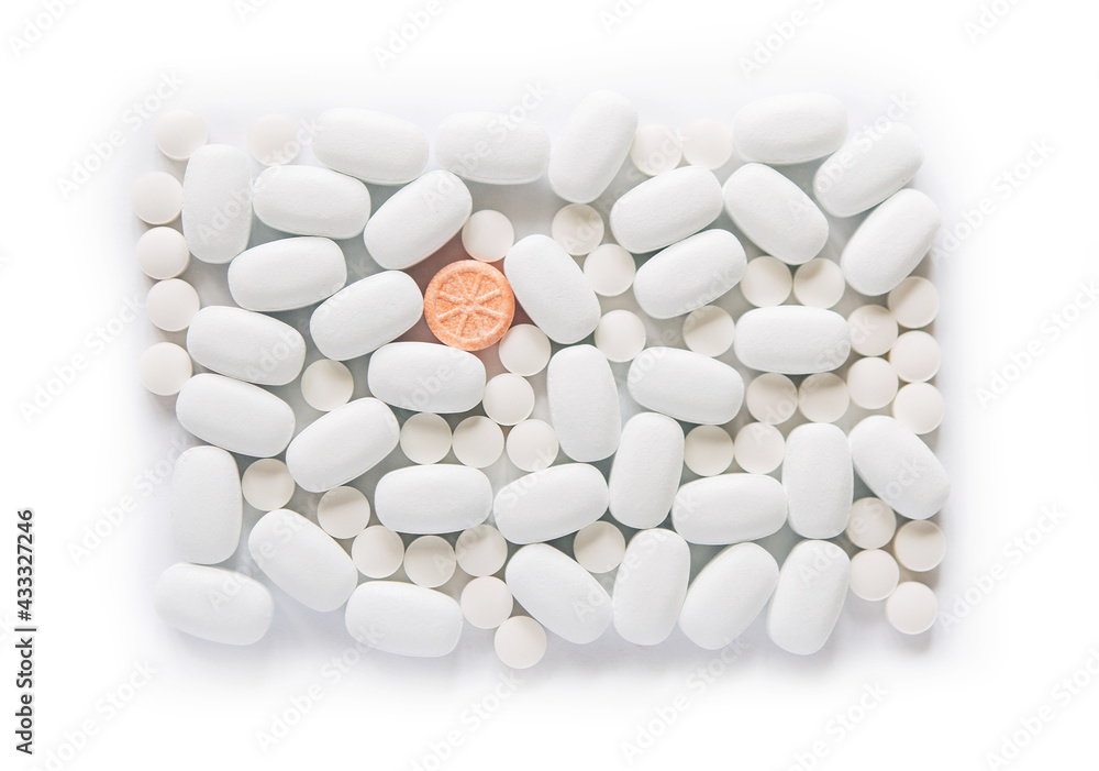 White pills on a white background. One bright orange round pill accent. Oblong and round pills close-up. Healthcare and medicine.