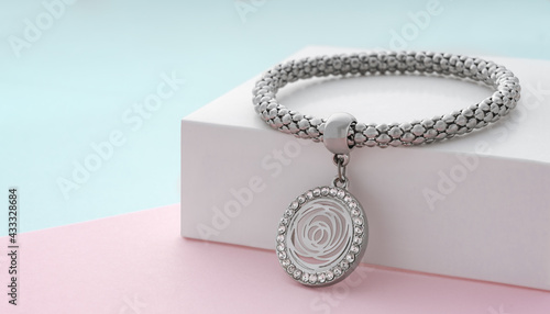 Silver bracelet with flower shape pendant on pastel colors background with copy space