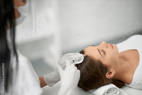 Фотография Side view of young cute brunette woman on procedure for improvements hair condition