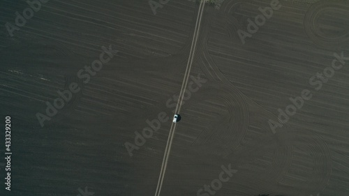 empty field top view, on a narrow road, a trail is symmetrically white car, graphic, geometric space, landscape abstraction