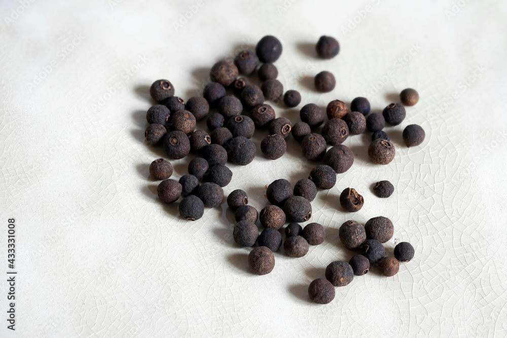 Allspice grains lying on a ceramic plate. Allspice, also known as Jamaica pepper, myrtle pepper, pimenta, or pimento. Allspice is one of the most important ingredients of Caribbean cuisine. Allspice grains lying on a ceramic plate. Allspice, also known as Jamaica pepper, myrtle pepper, pimenta, or pimento. Allspice is one of the most important ingredients of Caribbean cuisine.