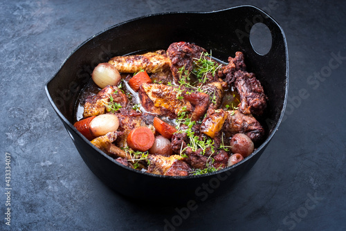 Modern style traditional French coq au vin with vegetable marinated in Burgundy sauce as close-up in a design casserole
