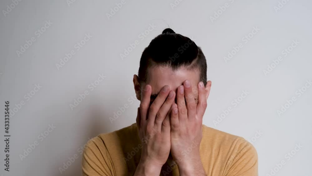 Young handsome European Caucasian man with beard shouts no and grabs his head with both hands. Person depicts the emotions of anger on white background. Young handsome European Caucasian man with beard shouts no and grabs his head with both hands. Person depicts the emotions of anger on white background.