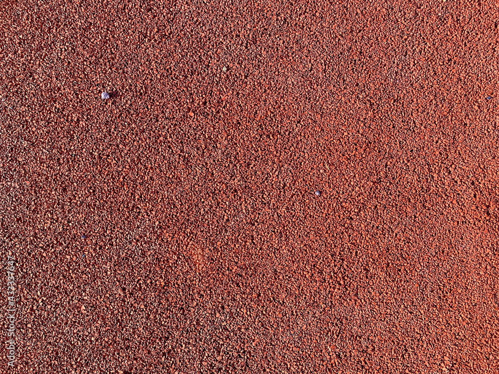 The red texture of the soft rubber surface of the safe cover of the sports playground for workout is made of pressed fine rubber. The background. Texture The red texture of the soft rubber surface of the safe cover of the sports playground for workout is made of pressed fine rubber. The background. Texture