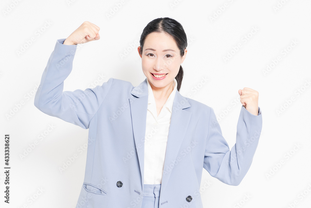 白バックの前に立って、ガッツポーズをする女性 白バックの前に立って、ガッツポーズをする女性