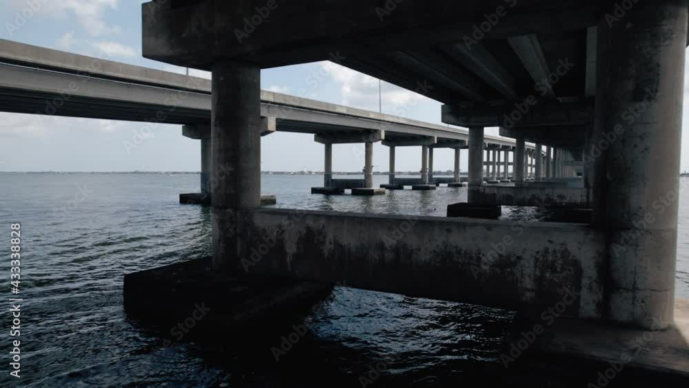Aerial shot flying through support structure of a coastal bridge. Cinematic wide shot Aerial shot flying through support structure of a coastal bridge. Cinematic wide shot