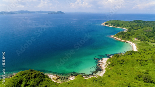 The reserved island of Furugelma on the ege of Primorsky Krai. View from above. Beautiful green island against the background of the blue sea.