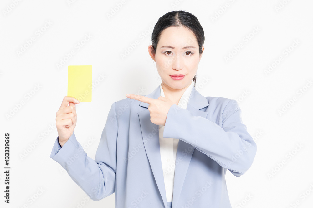 白バックの前に立って、イエローカードを示す女性 白バックの前に立って、イエローカードを示す女性