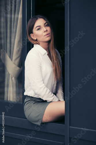 Young fashion woman in white shirt sitting on window
