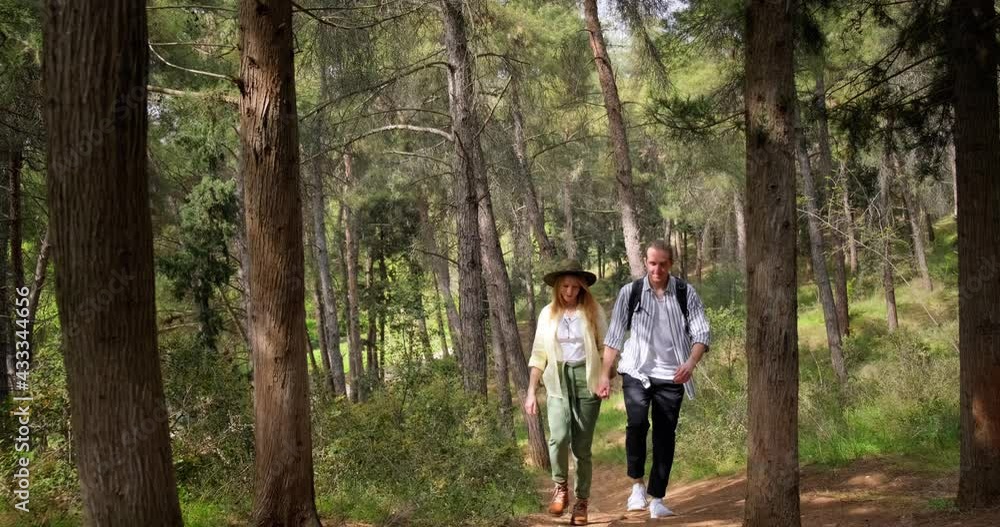 Young heterosexual loving couple walking in forest with backpacks and talking. Young heterosexual loving couple walking in forest with backpacks and talking.
