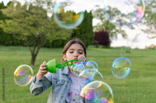 Hispanic girl playing in the park blowing soap bubbles