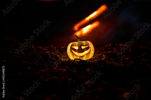 halloween jack-o-lantern on autumn leaves. Scary Halloween Pumpkin looking through the smoke. Glowing,