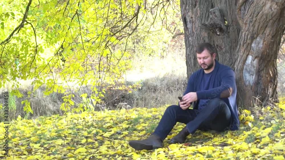 Charismatic man talking by phone in the park in autumn. Charismatic man talking by phone in the park in autumn.