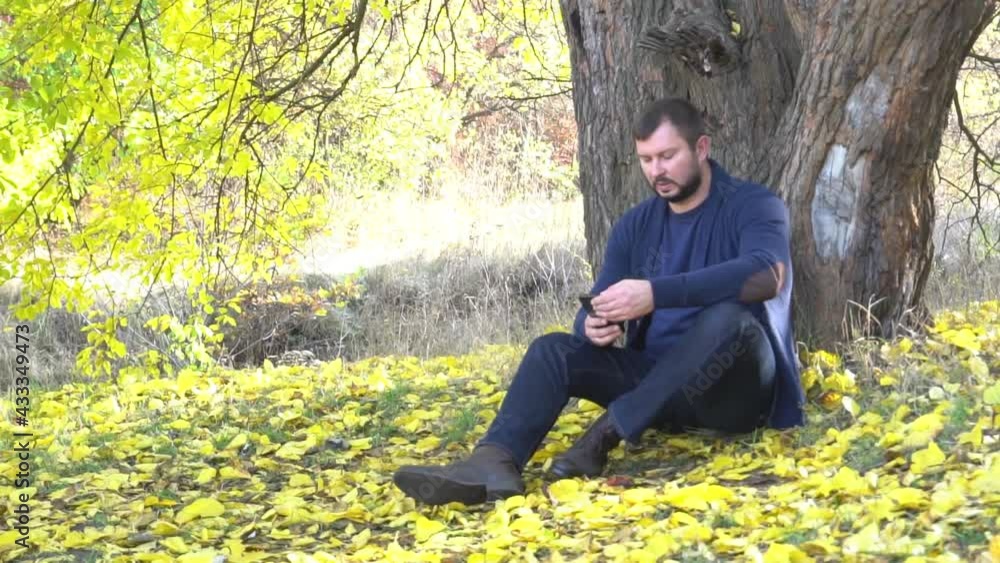 Slow Motion Handsome man using phone in autumn forest Slow Motion Handsome man using phone in autumn forest