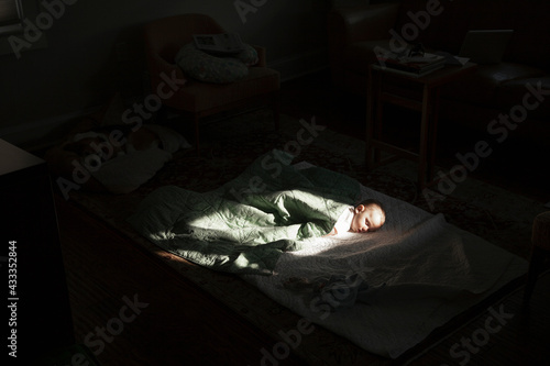 Baby boy sleeping in sunspot in bedroom photo