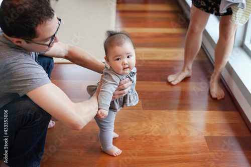 Father helping baby girl to stand photo