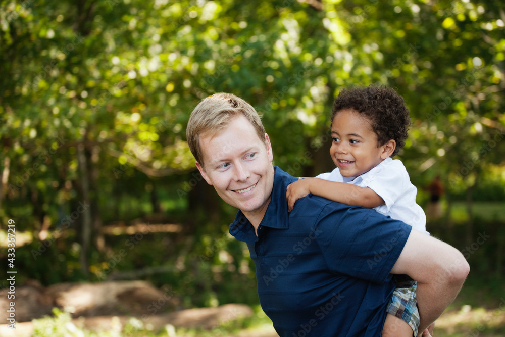 Side view of father giving son a piggyback smiling Side view of father giving son a piggyback smiling