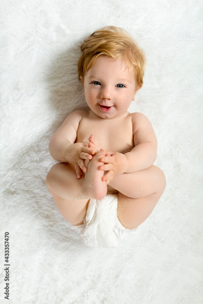 Toddler lying on blanket, holding feet, smiling Toddler lying on blanket, holding feet, smiling