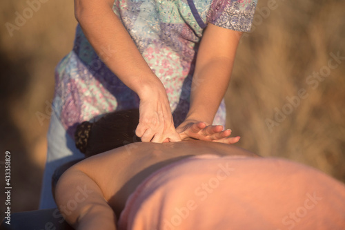 woman hands giving massage with knuckles to female back, outdoors