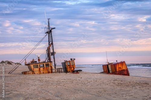 Fényképezés Rustic shipwreck being swallowed up by the sand with sunrise clouds