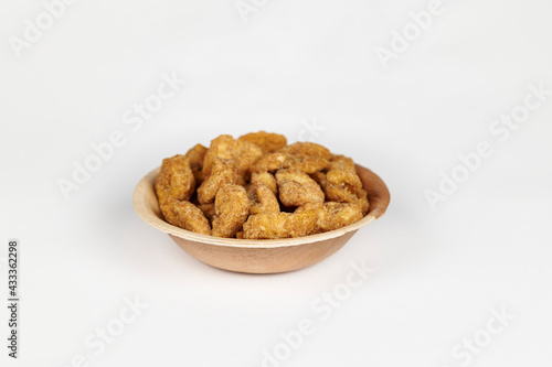 Jaggery coated banana chips or sharkara varatti in an areca leaf bowl on a white background