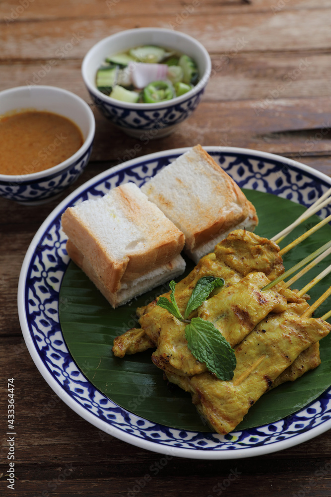 Local Thai food pork satay with oeanut dipping sauce isolated in wood background Local Thai food pork satay with oeanut dipping sauce isolated in wood background