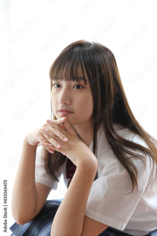 Portrait japanese school girl uniform sitting and look at camera in white tone bed room Portrait japanese school girl uniform sitting and look at camera in white tone bed room