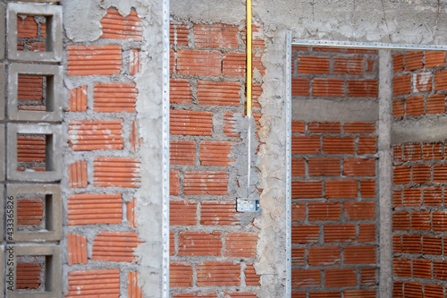 Yellow pipes are installed on the building wall to connect electric wires at various points in the construction building. Before plastering on the wall