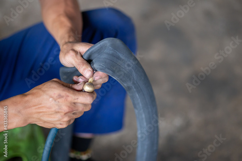 Closeup A motorbike mechanic's hand is inflating a tire. The inner tube of the motorbike that has leaked Checking for a tire leak