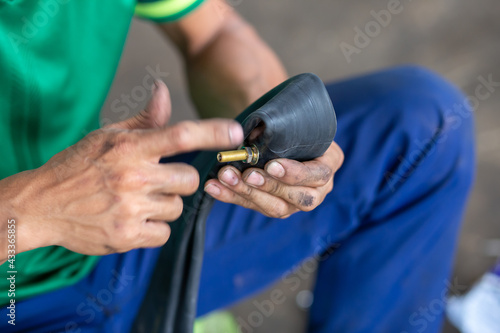 Close up the tire inflator nut of the motorbike. To bring the air out of the tire To patch a tire leak in a motorbike by a motorbike repairman