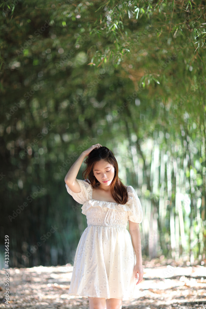 Beautiful young woman with white dress on bamboo forest background Beautiful young woman with white dress on bamboo forest background
