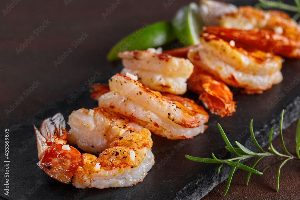 Fried prawn tails with lime and rosemary on black slate platter Fried prawn tails with lime and rosemary on black slate platter