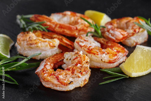 Fried scampi tails with lime, lemon and rosemary on black background