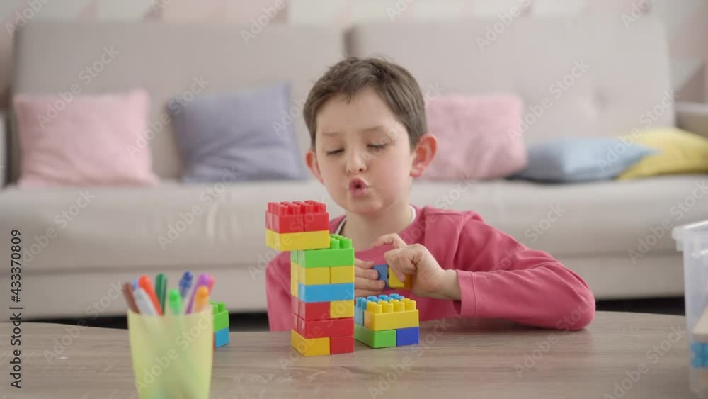 Happy cute little caucasian boy playing game building tower from colorful plastick constructor blocks, homeschool kid having fun at home, child development, playtime concept Happy cute little caucasian boy playing game building tower from colorful plastick constructor blocks, homeschool kid having fun at home, child development, playtime concept