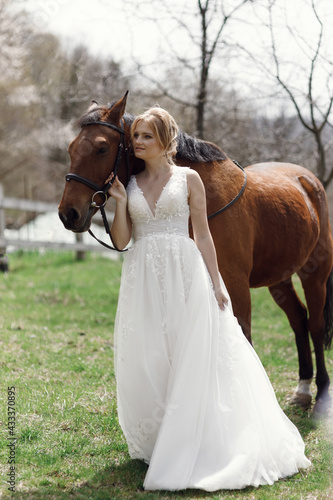 An attractive bride next to a horse. Wedding photography with a horse at sunset.