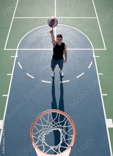 Basketball street player with basketball ball outdoor. Hand spinning basket ball. Balancing basketball on finger. © Volodymyr
