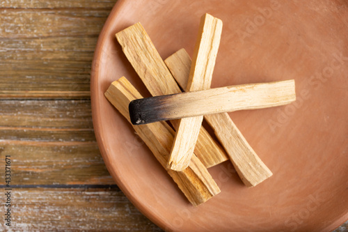 A top down view of a plate of palo santos incense burning sticks. 
