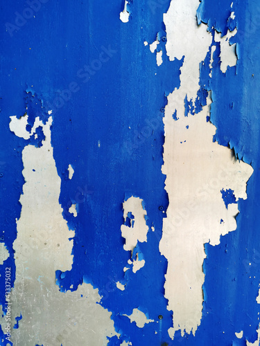 background of a very old wall painted with bright blue paint that has begun to flake off