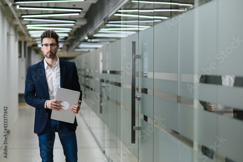 Wallpaper Mural a young business man in glasses and a jacket stands in the office. The manager is holding a laptop Torontodigital.ca