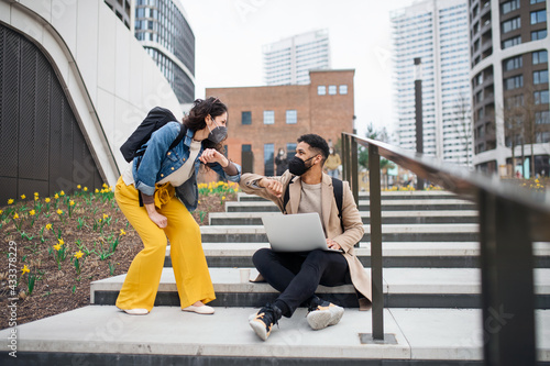 Man and woman friends greeting outdoors in city, coronavirus and back to normal concept. photo