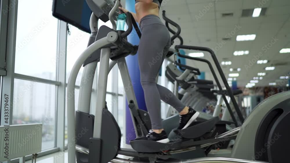 Young woman working out on orbi track at gym exercising