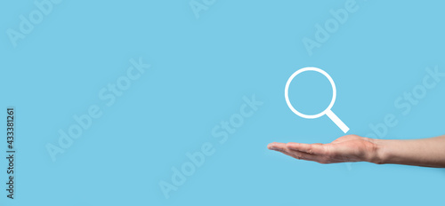 Male hand holding magnifying glass ,search icon on blue background. Concept search engine optimization, customer support.Browsing Internet Data Information.Networking Concept.