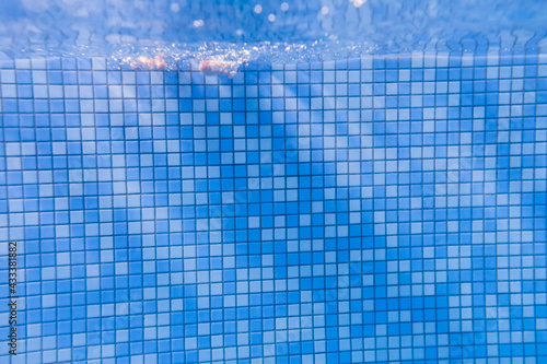 Feet of people moving under the water in the pool. Children legs. Summer. Funny underwater legs in swimming pool, under water view of women or kids, vacation and sport concept. Enjoy bubbles.