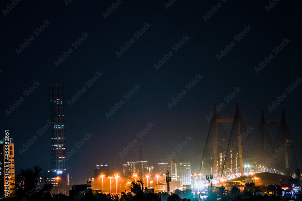 cityscape in the night of a bridge and a tall skyscraper in the nignat skyline from a distance